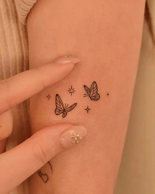 Small Minimalist Butterflies and Stars on Women Arm Tattoo by @tinytattooinc