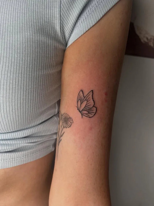 Small Minimalist Butterfly and Daisy on Women Arm Tattoo by @binkys_tattoo