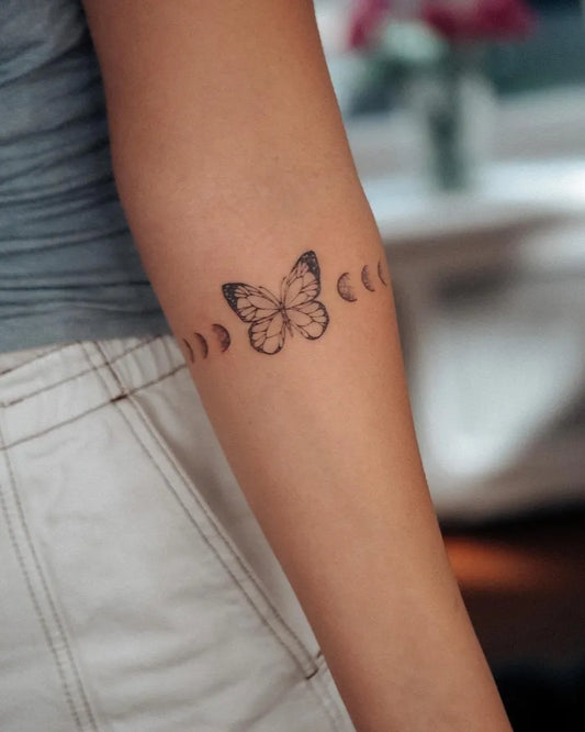 Small Minimalist Butterfly and Moon Phases Tattoo on Women Forearm by @bunami.ink