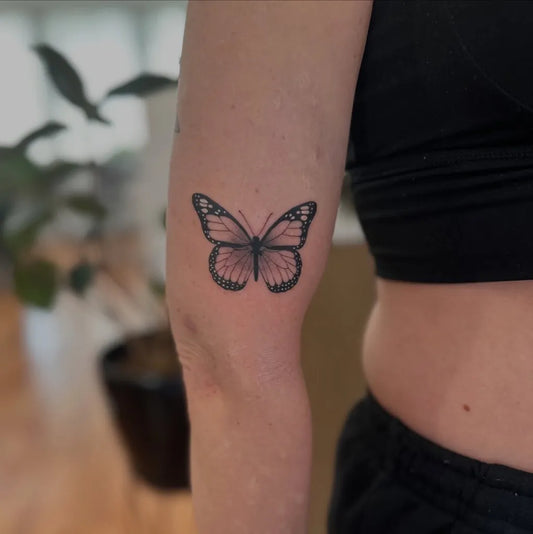 Small Minimalist Butterfly on Women Upper Arm Tattoo by @keeley.tattoo