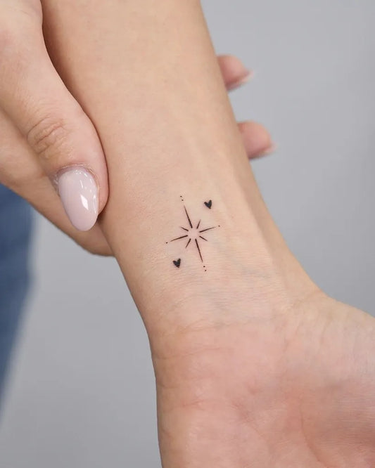 Small Minimalist Compass Star with Hearts Tattoo on Women Wrist by @gokce.karahasan