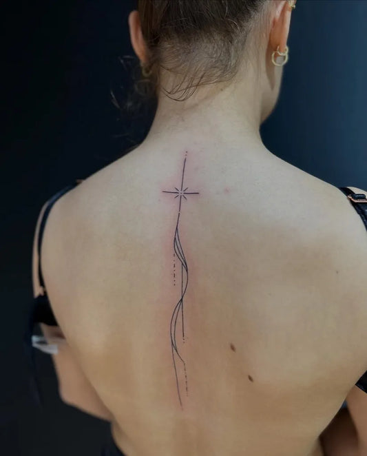 Small Minimalist Cross with Flowing Lines on Women Back Tattoo by @tattoosbycaner