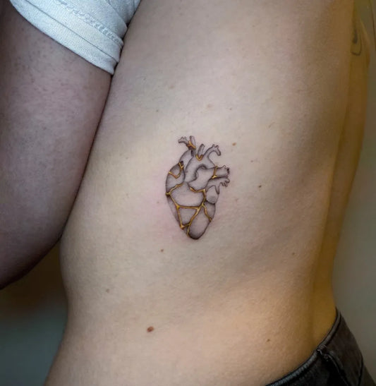 Small Minimalist Gold Kintsugi Heart on Men Rib Tattoo by @sailorstattoomilano