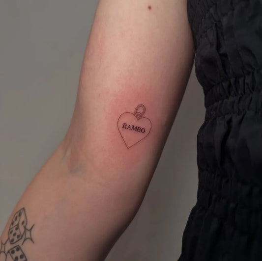 Small Minimalist Heart with Rambo text and chain on Women Arm Tattoo by @tommarkwick