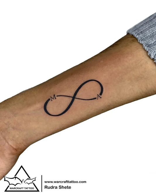 Small Minimalist Infinity Symbol with M and N Tattoo on Women Wrist by @warkrafttattoostudio