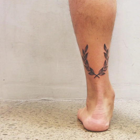 Small Minimalist Laurel Wreath Tattoo on Men Leg by @theo.pdf