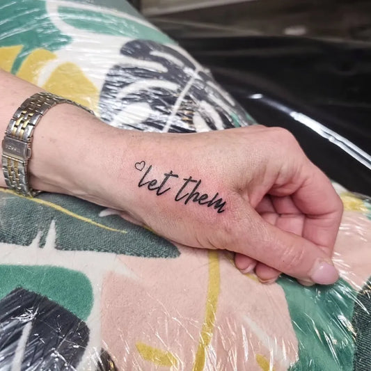 Small Minimalist Let Them Script on Women Wrist Tattoo by @lucykeystattoo