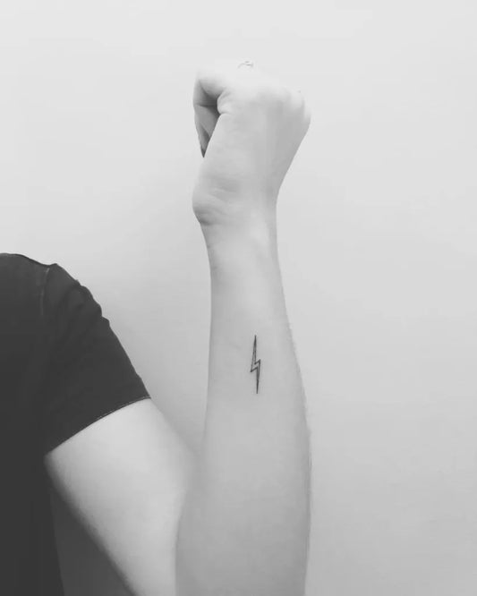 Small Minimalist Lightning Bolt Tattoo on Women Forearm by @finelinetattooantwerpen