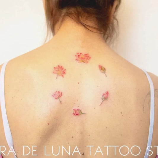 Small Minimalist Lotus Flowers on Women Back Tattoo by @claradelunastudio