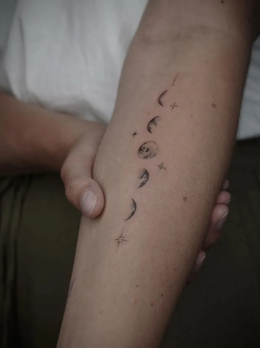 Small Minimalist Moon Phases and Stars Tattoo on Women Arm by @linesbynata