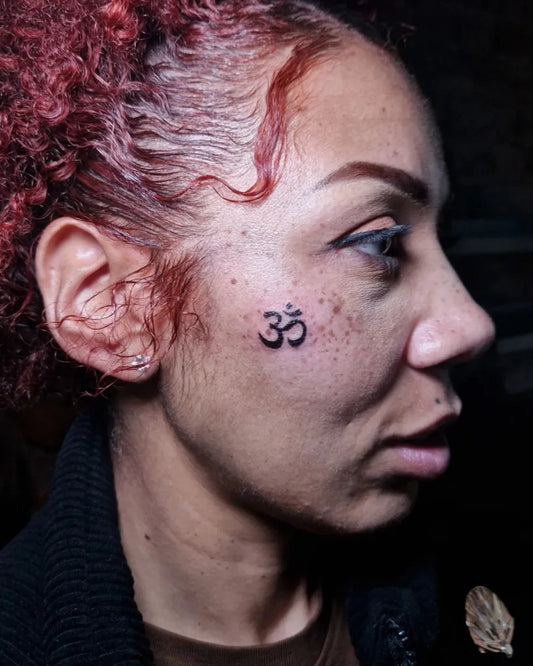 Small Minimalist Om on Women Face Tattoo by @anetao.tattoo