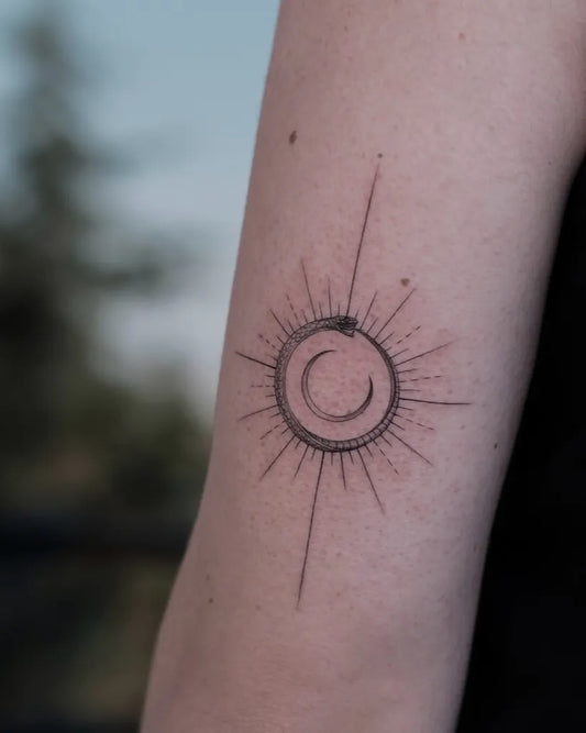 Small Minimalist Ouroboros Sunburst Tattoo on Women Arm by @belizozgun