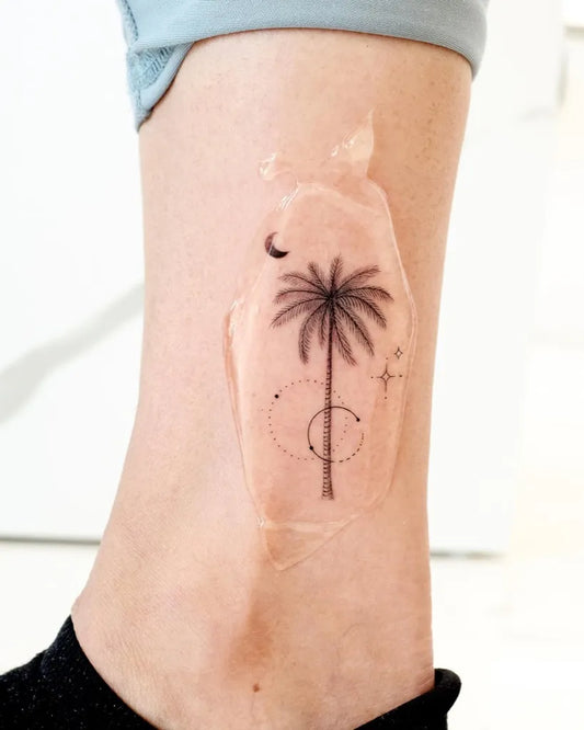 Small Minimalist Palm Tree and Crescent Moon Tattoo on Women Thigh by @lime_tattoo