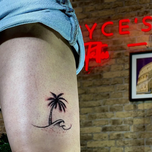 Small Minimalist Palm Tree and Wave Tattoo on Women Thigh by @greycestattoo
