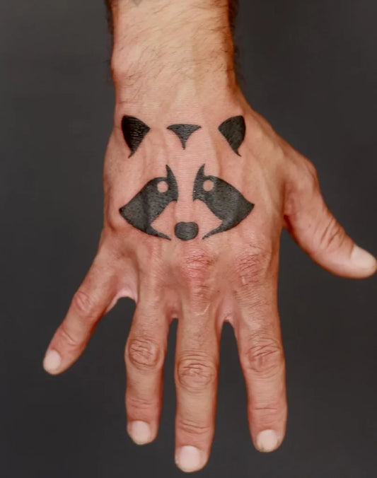 Small Minimalist Raccoon on Men Hand Tattoo by @celestialtattoo_