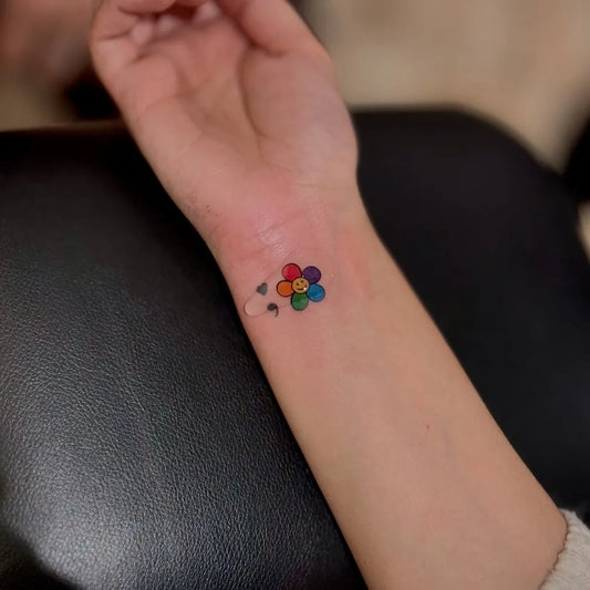 Small Minimalist Rainbow Flower on Women Wrist Tattoo by @rinktattooz