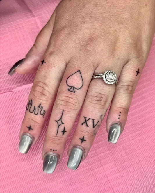 Small Minimalist Spade Stars Roman Numerals on Women Fingers Tattoo by @gloomybunny.ink