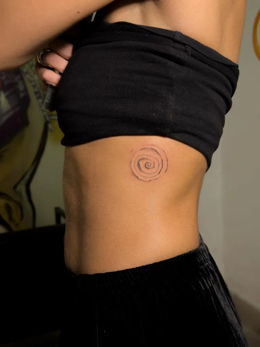 Small Minimalist Spiral Tattoo on Women Rib by @mortalbodytimelesstatts