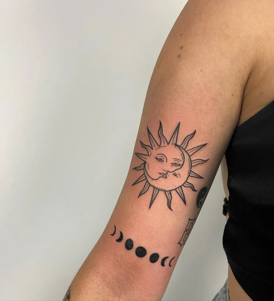 Small Minimalist Sun Kissing Moon with Moon Phases Tattoo on Women Arm by @hamortattoos