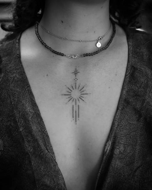 Small Minimalist Sun Star Cross on Women Sternum Tattoo by @mikhala.tattoos