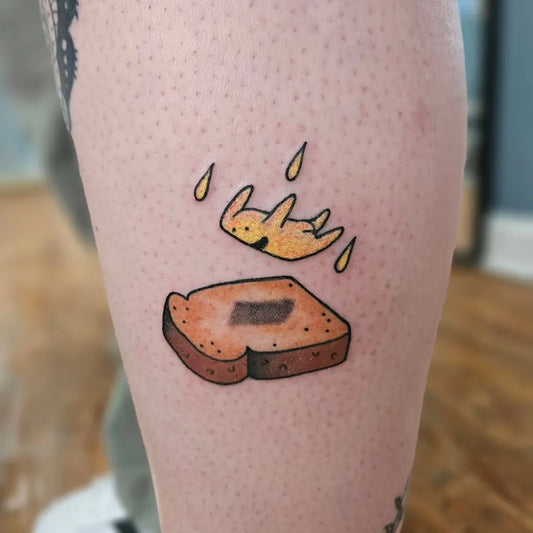 Small Minimalist Toast with Falling Crown on Women Thigh Tattoo by @bunchatats
