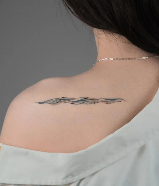 Small Minimalist Wave Tattoo on Women Shoulder by @moko.cjtattoo