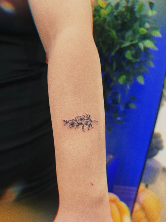 Small Minimalist flowers and leaves on Women Arm Tattoo by @sierratattooadana