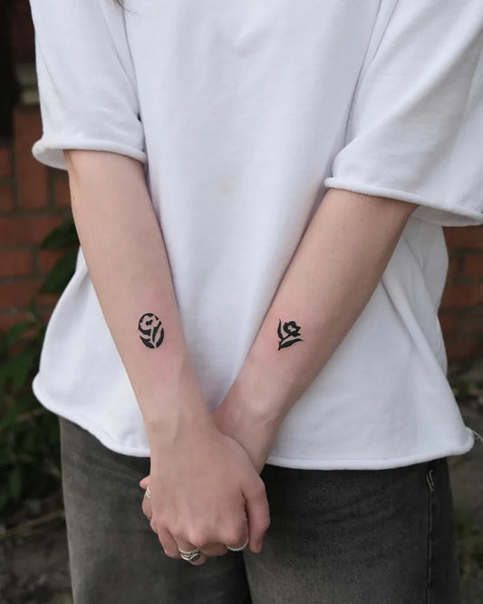 Small Negative Space Flower and Heart Tattoo on Women Arms by @surreal.lines