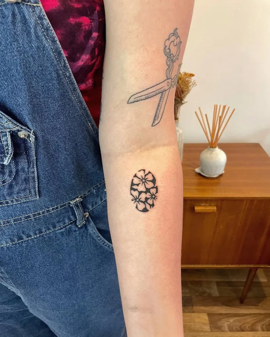 Small Negative Space Scissors and Flower Tattoo on Women Arm by @surreal.lines
