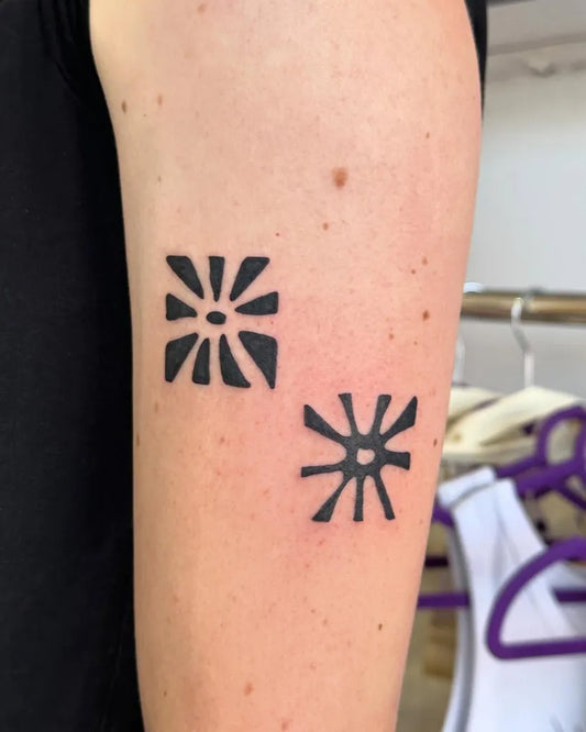 Small Negative Space Sunburst Tattoo on Women Arm by @stinky.tatts
