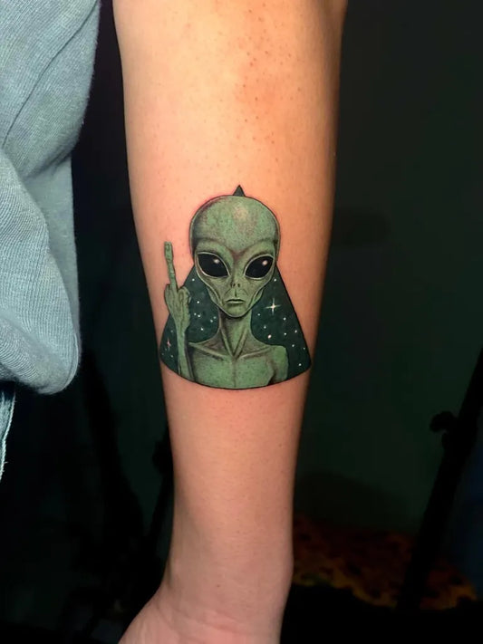 Small Neo Traditional Alien Showing Middle Finger Tattoo on Women Arm by @bahar.tattoo.art