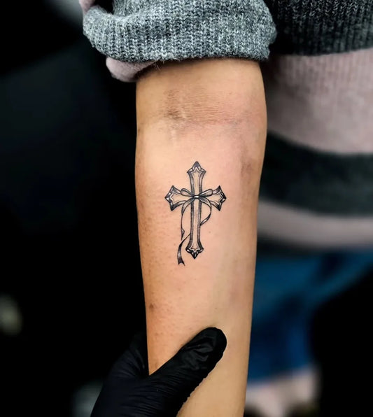 Small Neo Traditional Cross with Bow on Women Forearm Tattoo by @edd.ink_