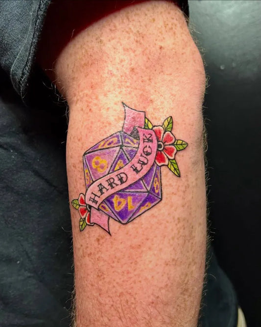 Small Neo Traditional Purple Dice with Ribbon and Flowers Tattoo on Men Arm by @koatlone