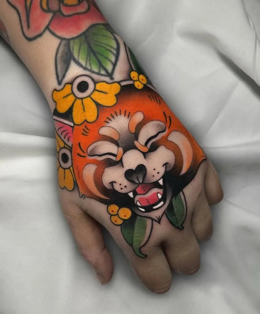 Small Neo Traditional Red Panda with Flowers on Women Hand Tattoo by @bhorn.tattoo