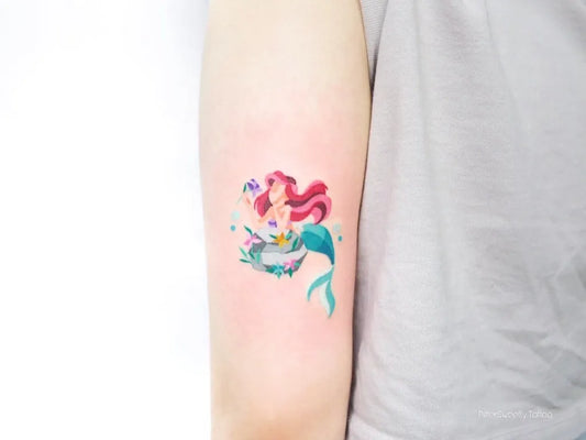 Small Neotraditional Ariel Mermaid Tattoo on Women Upper Arm by @bittersweetly.tattoo