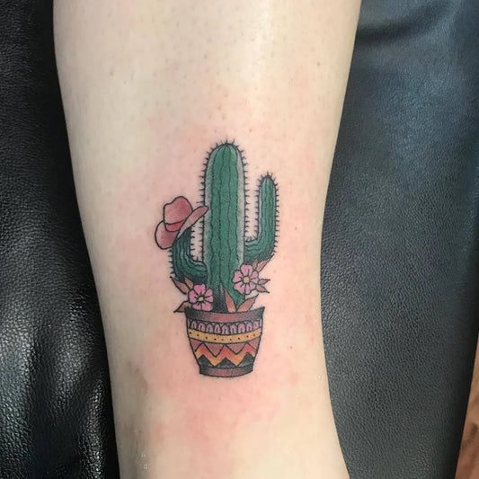 Small Neotraditional Cactus with Cowboy Hat and Pot Tattoo on Women Leg by @true_blue_tattoo