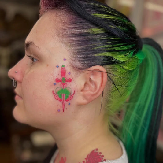 Small Neotraditional Dagger on Women Face Tattoo by @darciekaportattoo