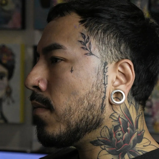 Small Neotraditional Laurel Cross Rose on Men Face Tattoo by @punto.tattoo.pdc