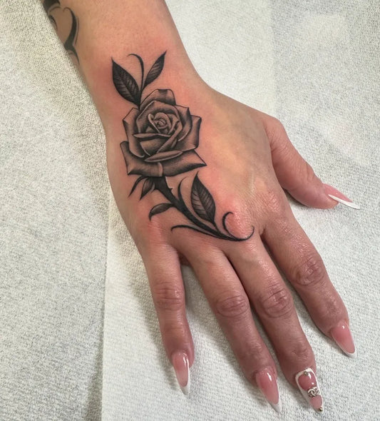 Small Neotraditional Rose with Leaves on Women Wrist Tattoo by @saul_tat2