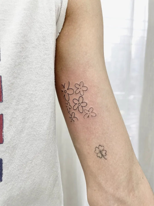 Small Outline Daisy and Four Leaf Clover Tattoo on Women Arm by @tattoo_thailand