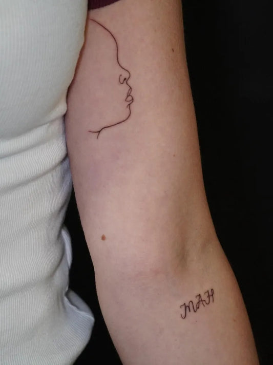 Small Outline Face and Text Tattoo on Women Arm by @ecoart_tattoo