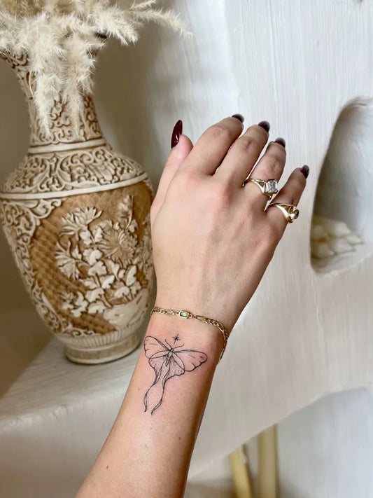 Small Outline Moth Tattoo on Women Wrist by @miagstattoo