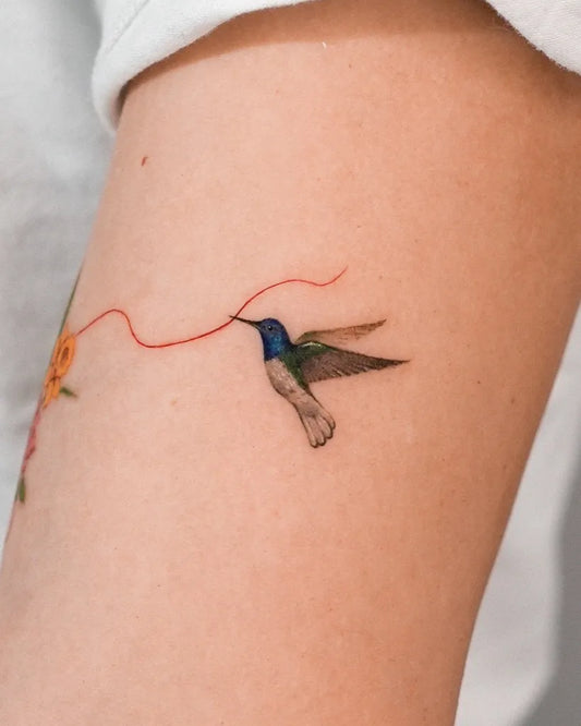 Small Realism Hummingbird with Flower and Red Thread on Women Arm Tattoo by @zihong_tattoo