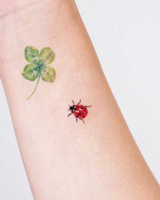 Small Realism Ladybug and Four Leaf Clover Tattoo on Women Wrist by @e.ple_tattoo