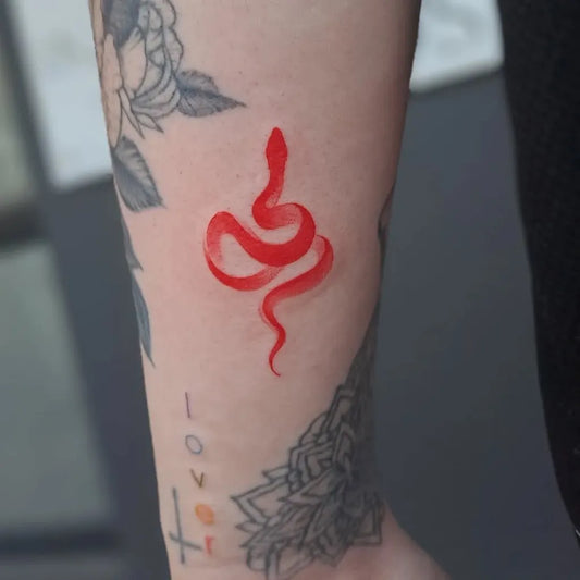 Small Red Snake Tattoo on Women Arm by @ingoodhandstattoos