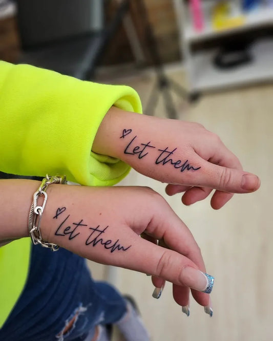Small Script Let Them Phrase on Women Hand Tattoo by @leightsphillipstattoos
