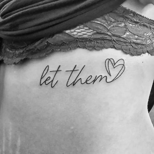 Small Script Let Them and Heart on Women Rib Tattoo by @tainted_love_tattoo