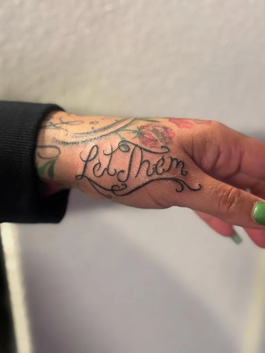 Small Script Let Them and Roses on Women Hand Tattoo by @vics_art_studio