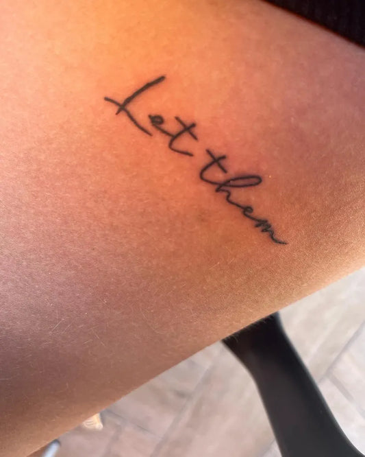 Small Script Let Them on Women Thigh Tattoo by @lisa.marie0684
