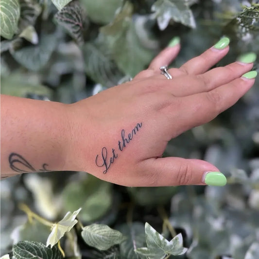 Small Script Let Them on Women Wrist Tattoo by @openwatertattoos